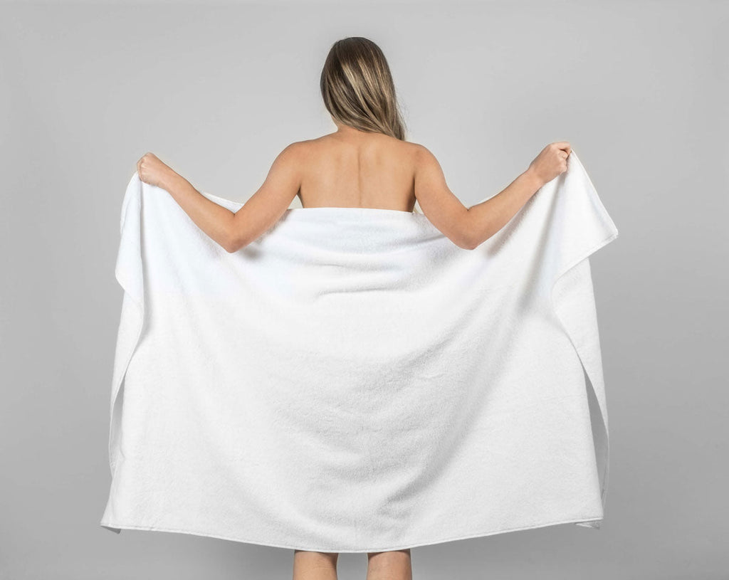 Woman holding a white Turkish cotton towel after workout, representing Hencely gym and fitness towel collection.