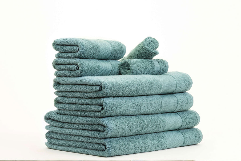 Stack of folded Turkish towels in soft pastel tones on a wooden surface, showcasing luxury and absorbency.