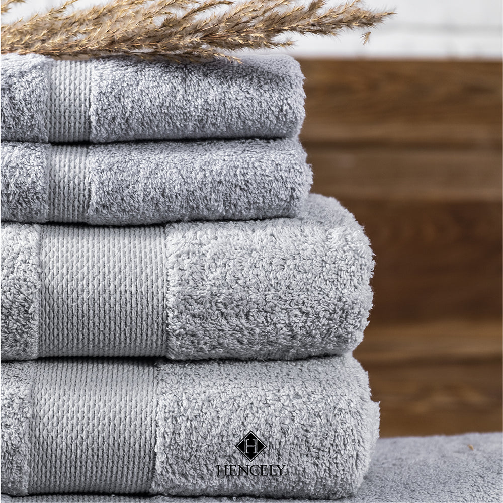 Stacked silver cotton bath sheets neatly folded, showing soft texture and absorbent fabric close-up.