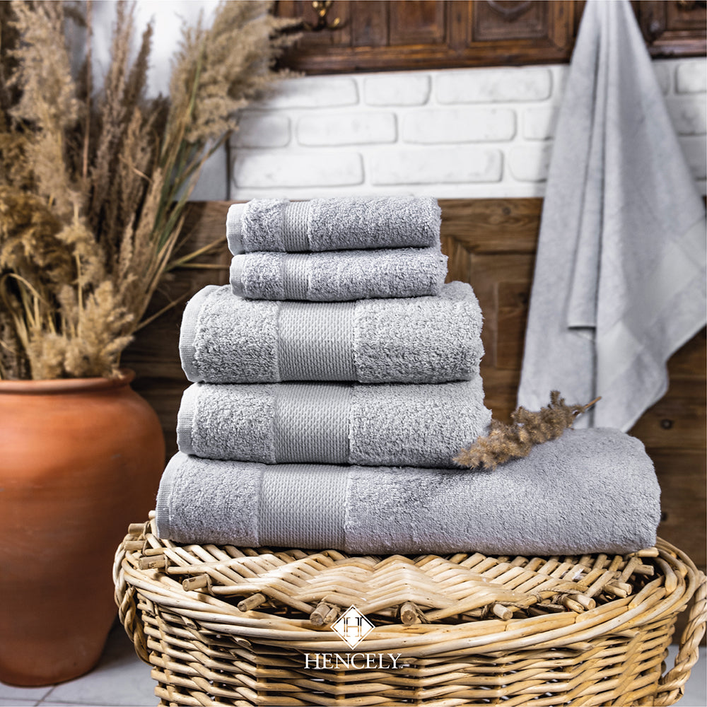 Stacked silver bath sheets displayed in a woven basket with rustic home decor, highlighting softness and elegance for bathroom styling.