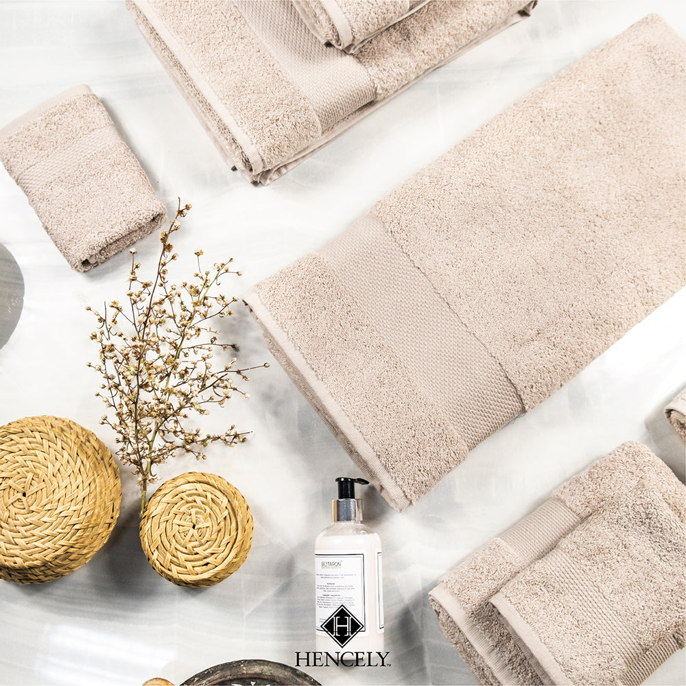 Flat lay of beige Turkish cotton bath sheets arranged with natural baskets, soap dispenser, and decorative branches, highlighting a spa-inspired bathroom look.