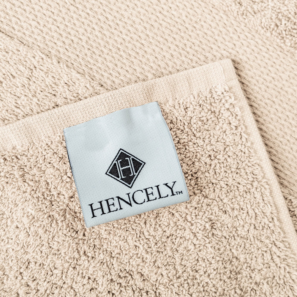 Close-up of Hencely beige bath sheet with stitched brand label, soft Turkish cotton fabric texture.