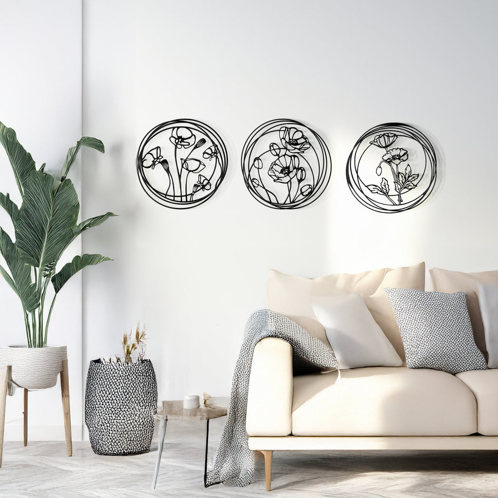 Three round floral black metal panels displayed above a stylish sofa.