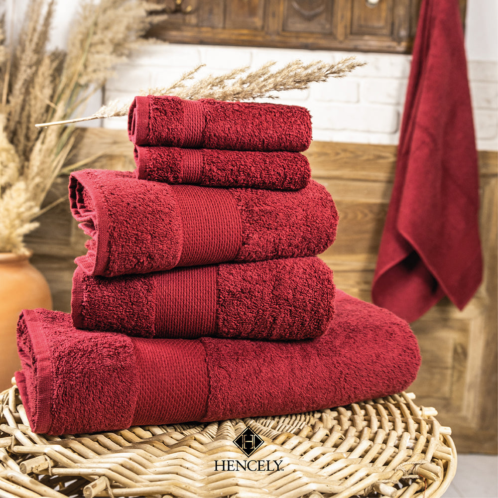 Stacked red cotton bath sheets by Hencely, neatly folded on a wicker basket with rustic bathroom decor