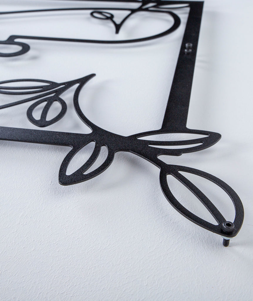 Close-up of black line art metal wall decor showing floral frame details and fine craftsmanship.