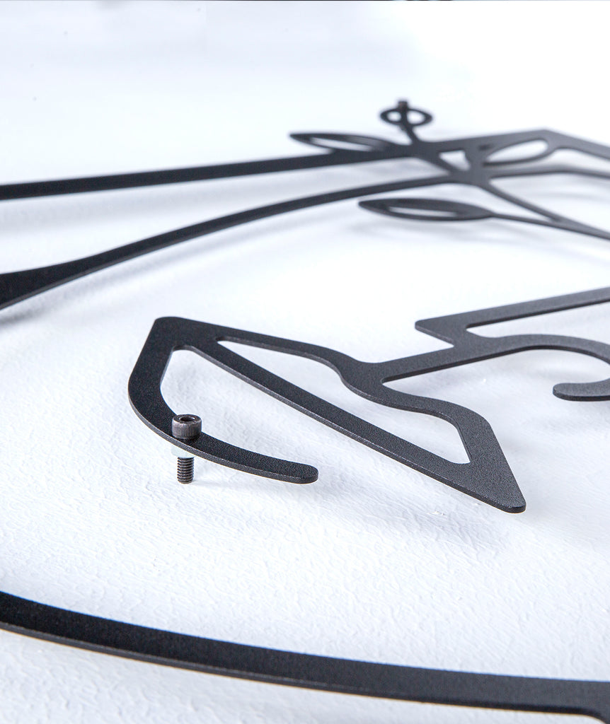 Close-up of black line art metal wall decor showing the female face outline and sturdy frame detail.